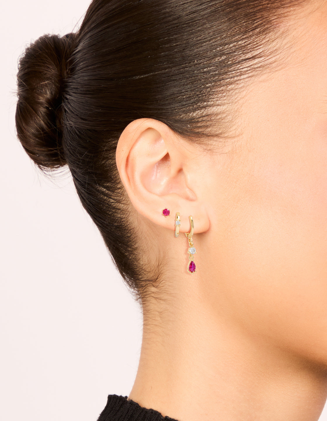 Featuring gold plated dark pink cubic zirconia studs and huggie earrings in a dainty 3-pack with crystal accents on ear view