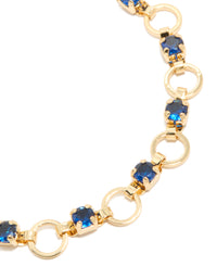 Showcasing a gold plated bracelet with blue cubic zirconia in round cut and alternating link design close up view - link has visual effect only