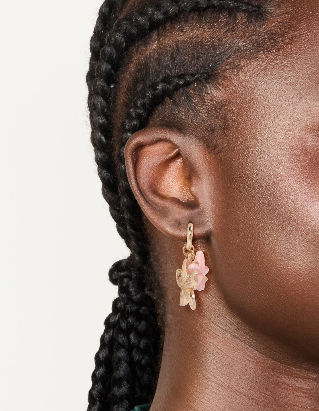 Crafted with dainty gold huggie earrings featuring pearl, pink flower, and starfish ocean theme charm drops in light pink and white on ear view