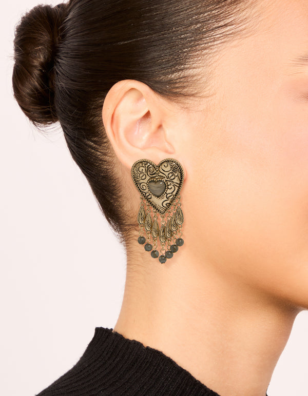 Featuring antique gold textured heart drop earrings with beads, and charm details in statement style on ear view