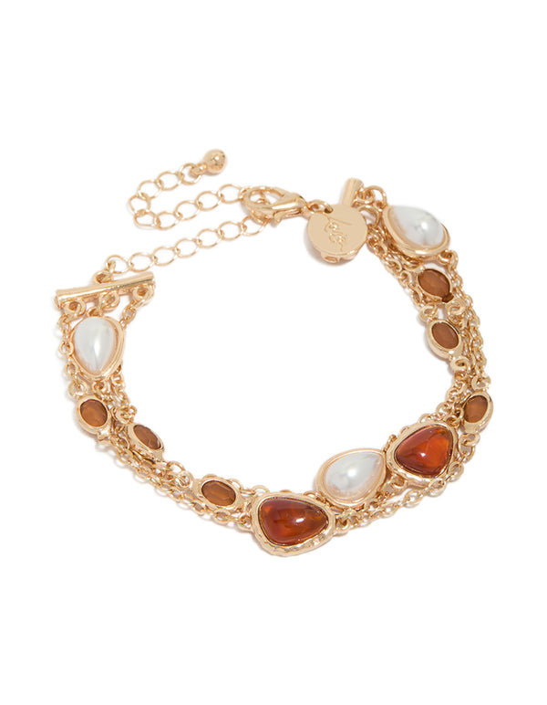 Showcasing a gold bracelet with pearl and orange jewel accents in a front view