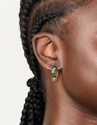 Showcasing thick huggie earrings with floral pattern in enamel, statement style, gold and black with pink accents on ear view - link has visual effect only