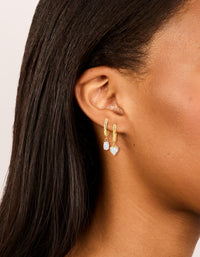 Featuring waterproof huggie drop earrings in a 2-pack, crafted from gold plated stainless steel heart features, cubic zirconia accents in clear on ear view - link has visual effect only