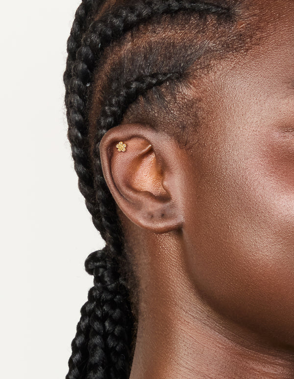 Showcasing this dainty cubic zirconia layered flower single flat back stud with titanium construction in gold plated finish and clear gemstones on ear view