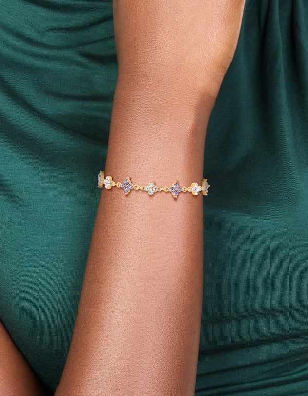 Highlighting a floral bracelet crafted from gold plated materials with cubic zirconia in purple on wrist view